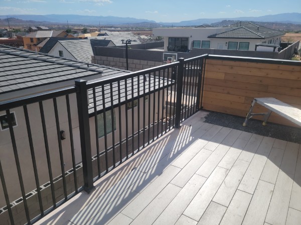 Balcony deck surface, black rails and wood privacy wall.