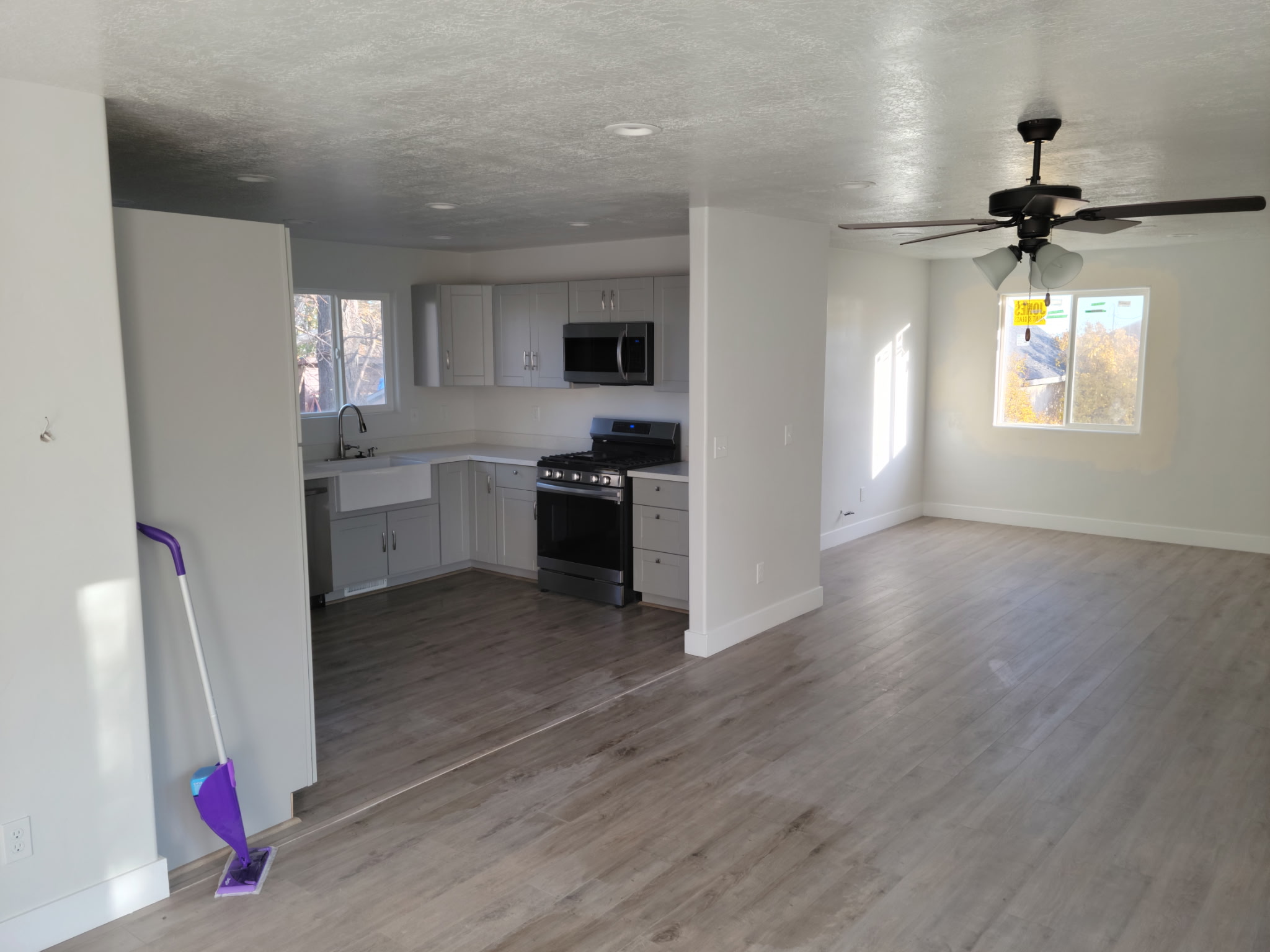 White kitchen cabinets, farmhouse sink and installed range beside the living area.