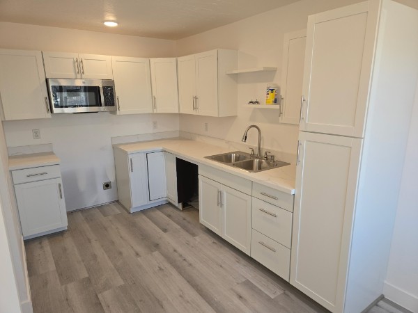 L-shaped white kitchen with a double sink and tall pantry.