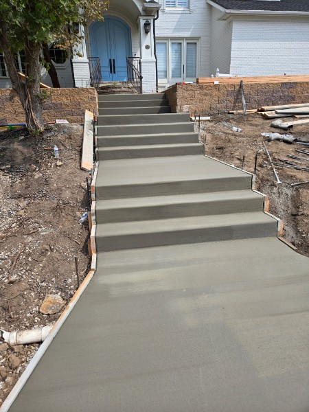Concrete entry stairs rising between block walls toward blue double doors.